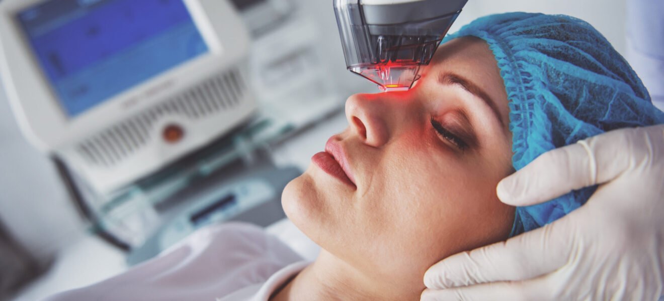 Beautiful female patient is getting a face skin treatment while lying at cosmeticians office, close up